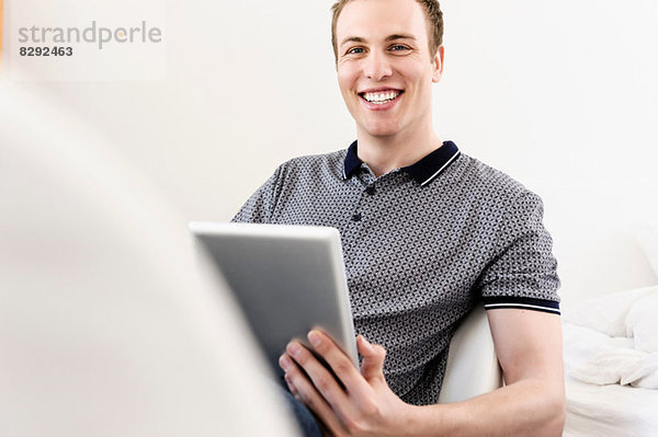 Porträt eines jungen Mannes sitzend mit digitalem Tablett