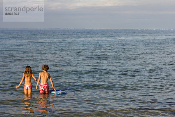 Bruder und Schwester beim Paddeln im Meer