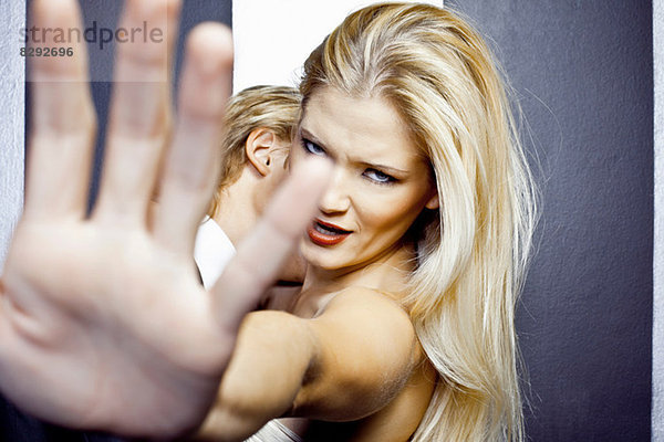 Nahaufnahme einer jungen wütenden Frau mit der Hand vor der Kamera