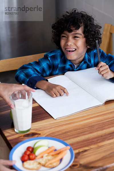 Junge macht Hausaufgaben  Person  die Snacks und Milch serviert