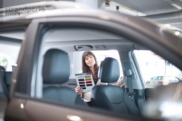 Mittlere erwachsene Frau mit Farbmuster im Autohaus