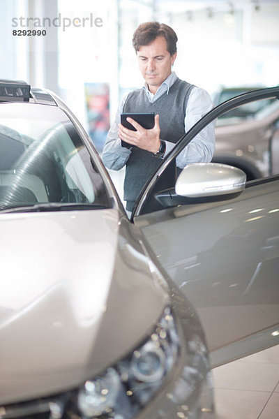 Mittlerer Erwachsener Mann mit Taschenrechner im Autohaus