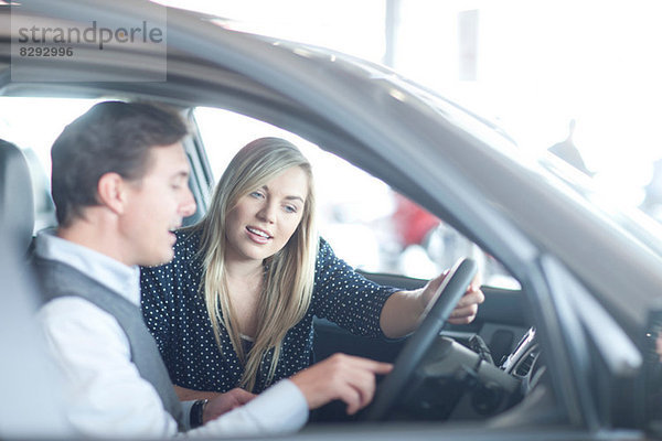 Autoverkäufer berät junge Frau im Autohaus
