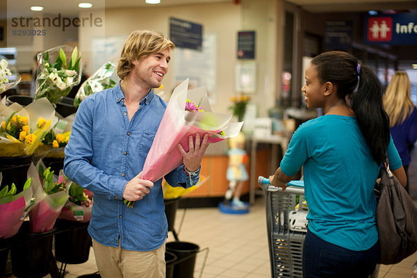 Junger Mann beim Einkaufen Blumenstrauß auswählen