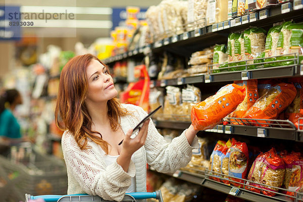 Shopperin mit digitalem Tablett im Supermarkt
