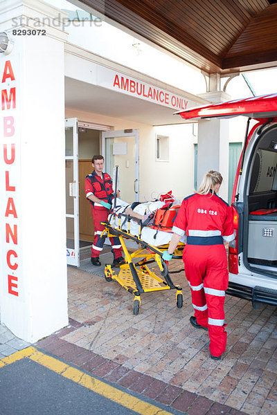 Rettungssanitäter bewegen den Patienten durch die Tür des Krankenhauses