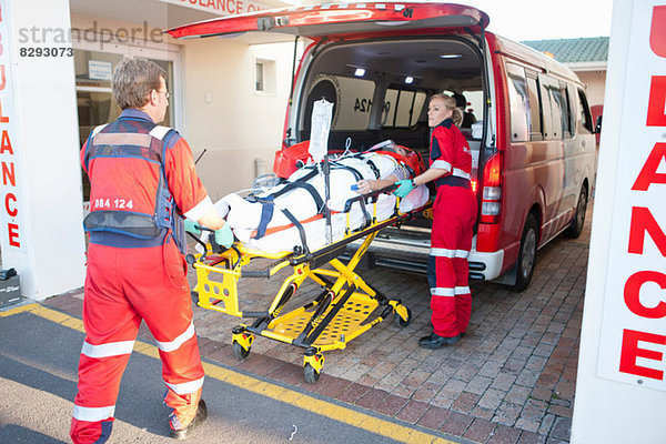 Rettungssanitäter beim Anheben des Patienten aus dem Krankenwagen