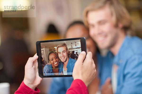 Gruppe von Freunden im Café fotografieren mit digitalem Tablett
