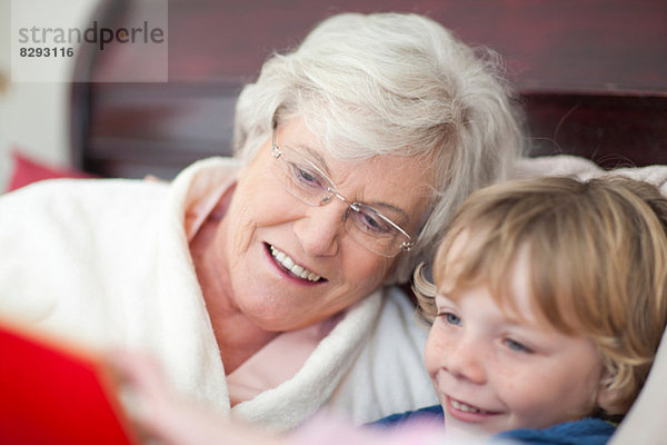Großmutter und Enkel lesen Märchenbuch im Bett