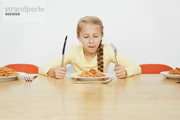 Mädchen am Tisch sitzend mit Spaghettiteller