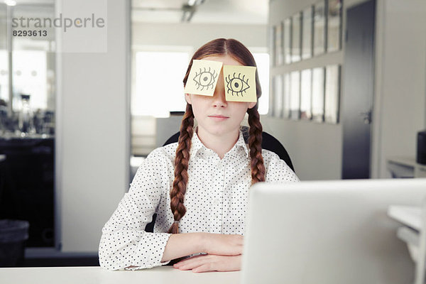 Mädchen im Büro mit Haftnotizen für die Augen