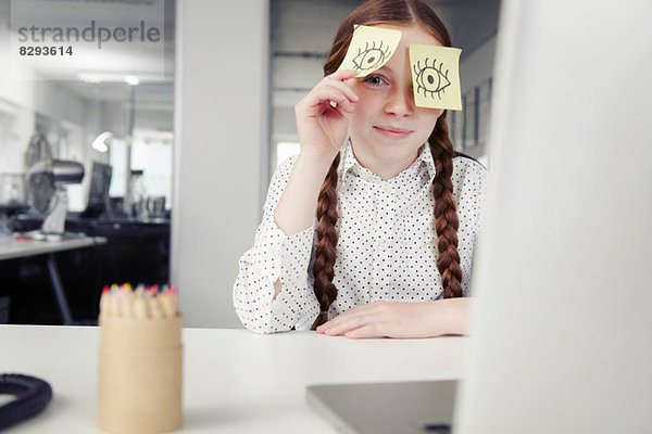 Mädchen im Büro mit Haftnotizen  die die Augen bedecken  spähend