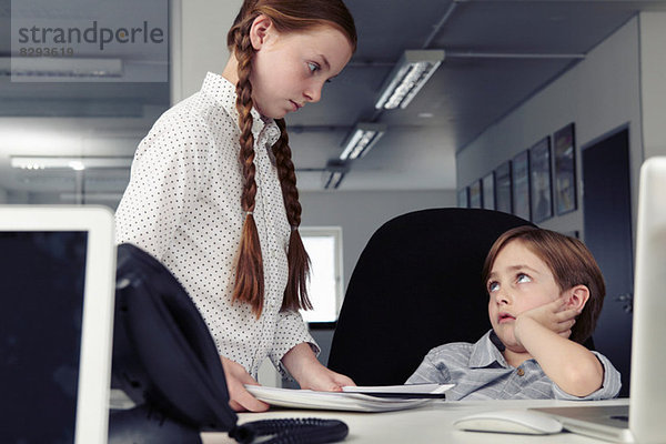 Junge am Schreibtisch mit missbilligendem Mädchen