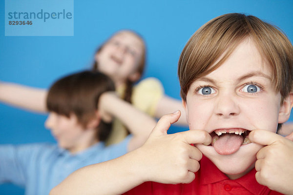 Porträt eines Jungen mit herausgestreckter Zunge  blauer Hintergrund