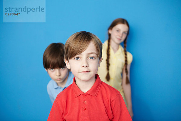 Porträt von drei Kindern mit Blick auf die Kamera  blauer Hintergrund