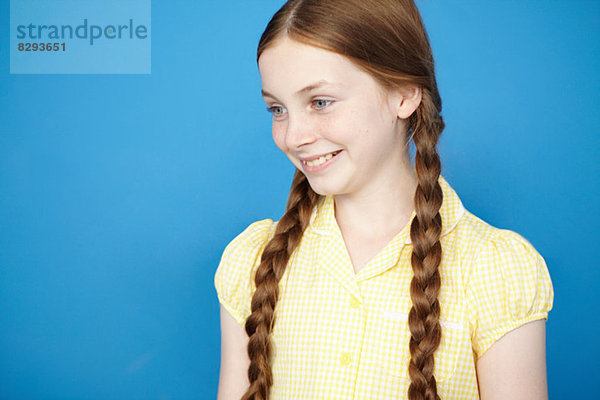 Porträt eines Mädchens mit Zöpfen in gelbem Schulkleid