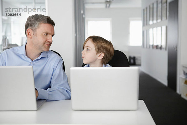 Vater und Sohn mit Laptops  von Angesicht zu Angesicht