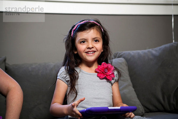 Kind mit digitalem Tablett auf Sofa