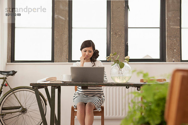 Junge Frau am Tisch sitzend mit Computer