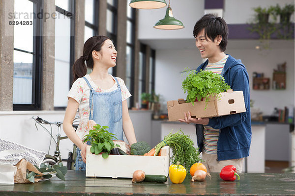 Portrait eines jungen Paares in der Küche mit Kräutern und Gemüse
