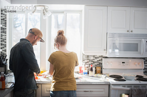 Mittleres erwachsenes Paar bei der Zubereitung von Speisen in der Küche