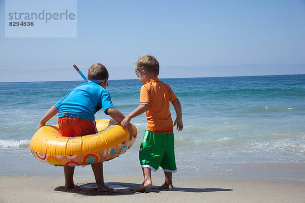 Zwei junge Brüder spielen mit Gummiring am Strand