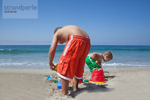 Zwei junge Brüder bauen Sandburgen am Strand