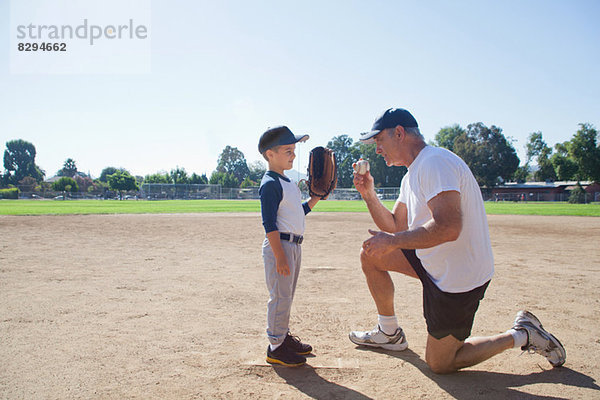 Mann im Gespräch mit Enkel auf dem Baseballfeld