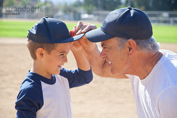 Junge und Großvater in Baseballkappen  von Angesicht zu Angesicht