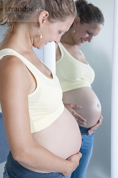 junge schwangere Frau vor dem Spiegel
