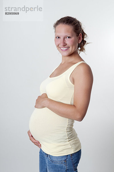 Lächelnde junge schwangere Frau  Studioaufnahme