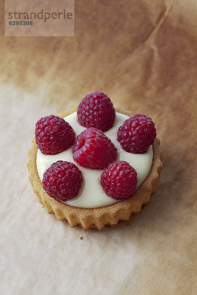 Pie with vanilla pudding and raspberries on baking paper  studio shot