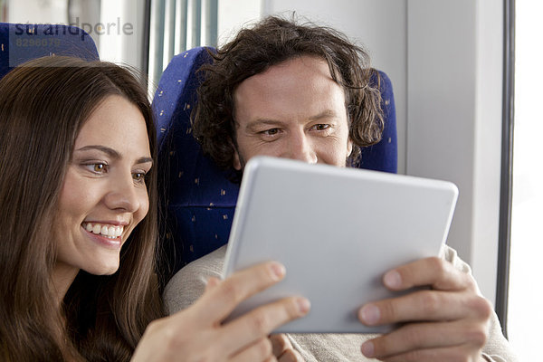 Couple using digital tablet in a train