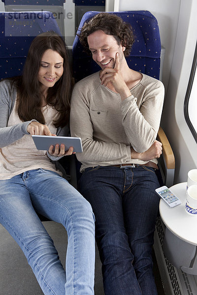 Couple using digital tablet in a train