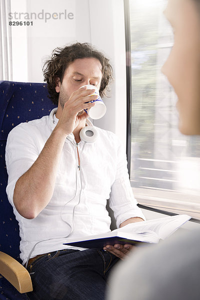 Mann trinkt Kaffee im Zug