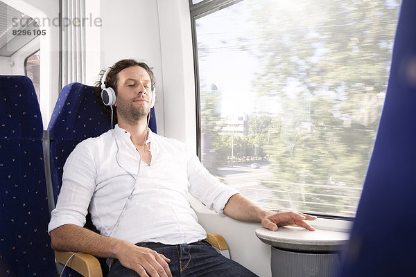 Mann mit Kopfhörer im Zug