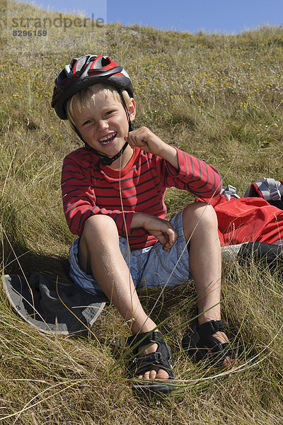 Frankreich  Bretagne  Landeda  Junge mit Helm in der Düne sitzend