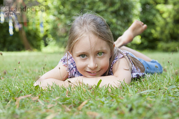 Lächelndes Mädchen im Gras liegend