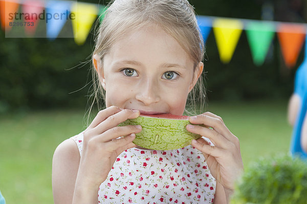 Glückliches Mädchen isst Wassermelone auf einer Geburtstagsparty