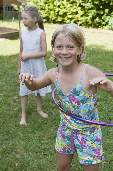 Glückliches Mädchen mit Hula-Hoop im Garten