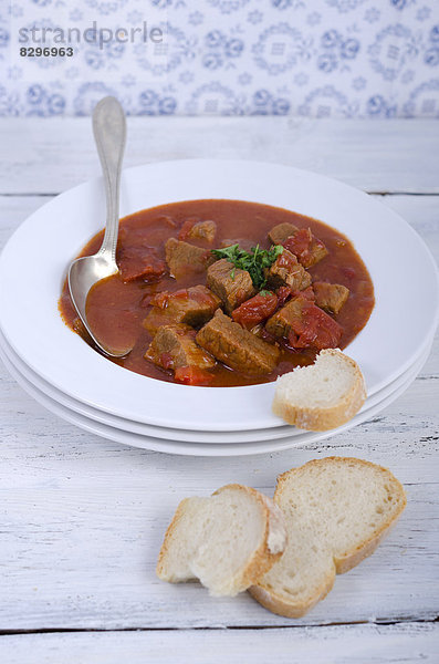 Goulash soup with bread on wooden table