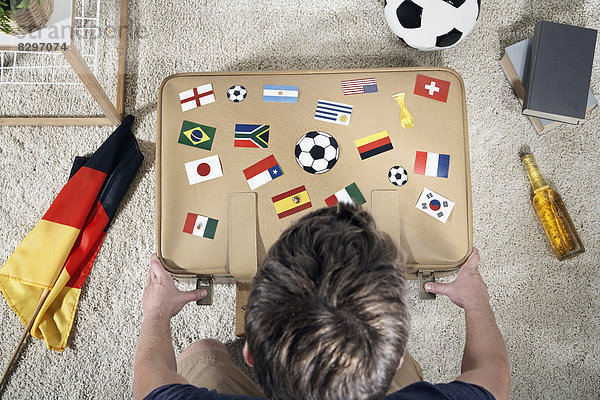 Soccer fan with national flags on suitcase