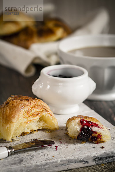 Croissants with milk coffee and jam on wooden board  studio shot