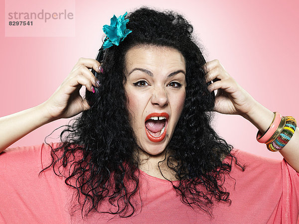 Portrait of screaming young woman with headphones  studio shot