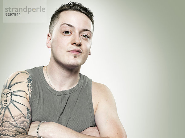 Portrait of young man with tatoo on his right upper arm  studio shot
