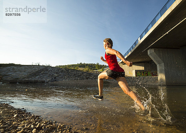 sportliche junge Frau läuft durch den Rems-Fluss