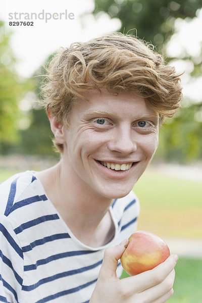 Young man eating an apple outdoors