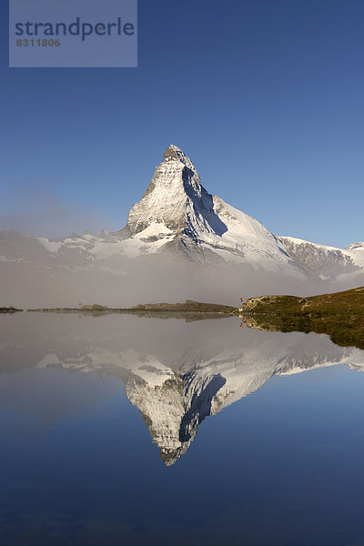 Matterhorn spiegelt sich im Stellisee  mit Nebel