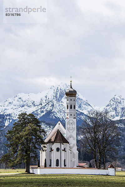 Kirche St Coloman  hinten die verschneiten Alpen