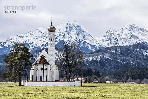 Kirche St Coloman  hinten die verschneiten Alpen